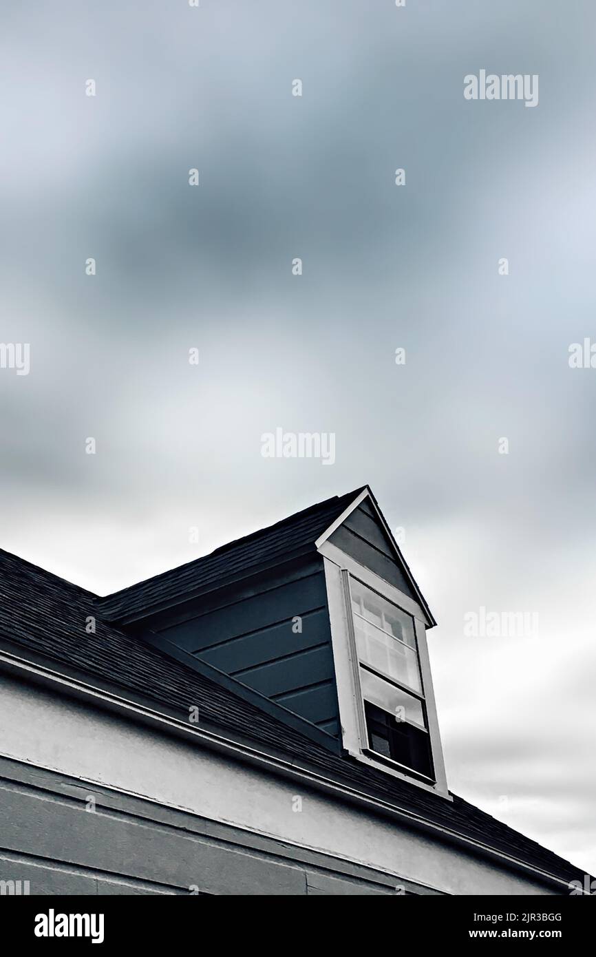 Un plan à faible angle d'une fenêtre de dortoir sur le toit d'une maison sous un ciel sombre Banque D'Images