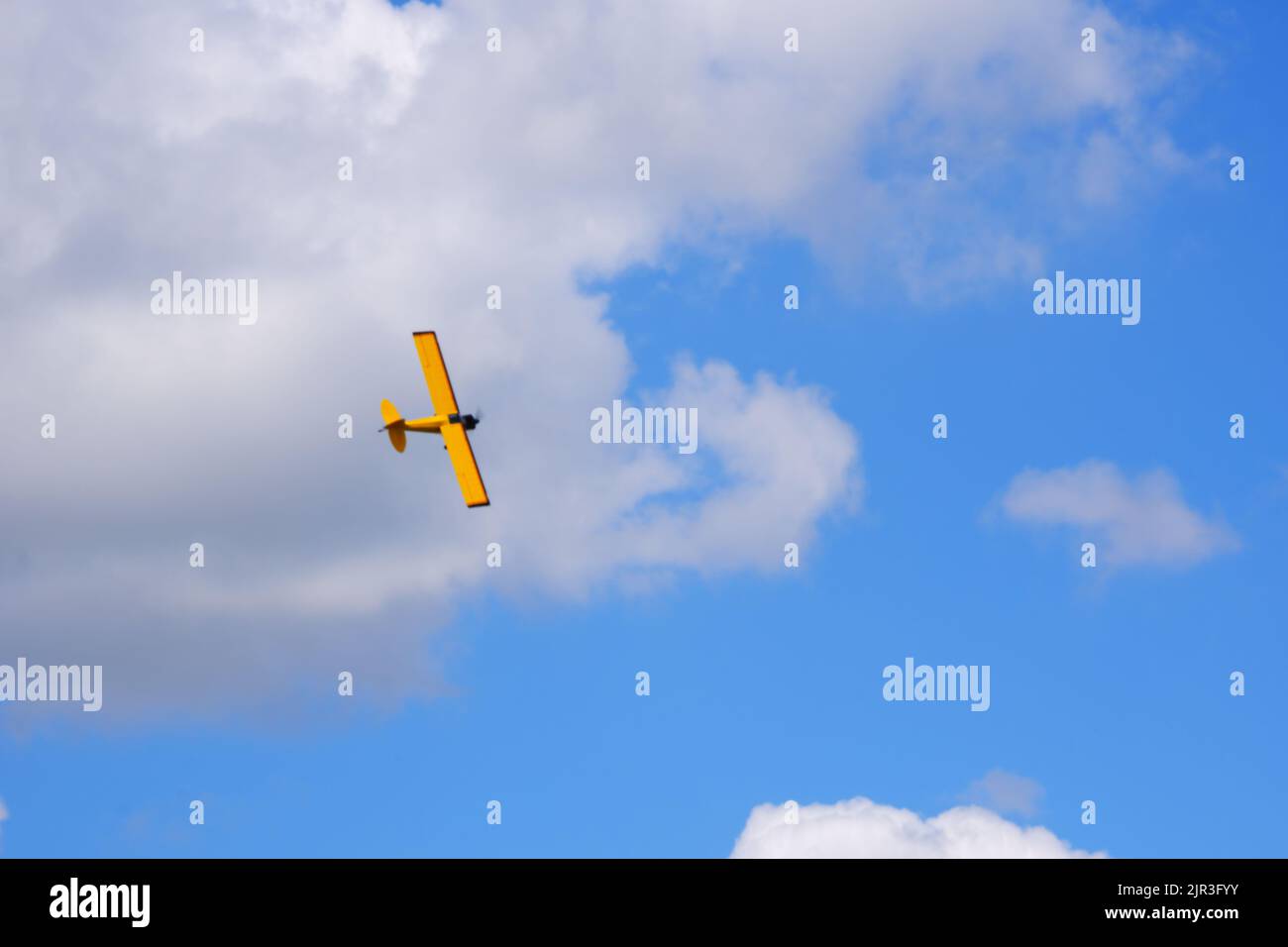 Avion d'hélice jaune à moteur unique volant dans un ciel bleu ciel nuageux par jour d'été Banque D'Images