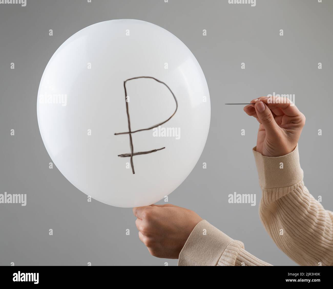 Une femme caucasienne fait apparaître un ballon avec une inscription rouble et une aiguille. Banque D'Images