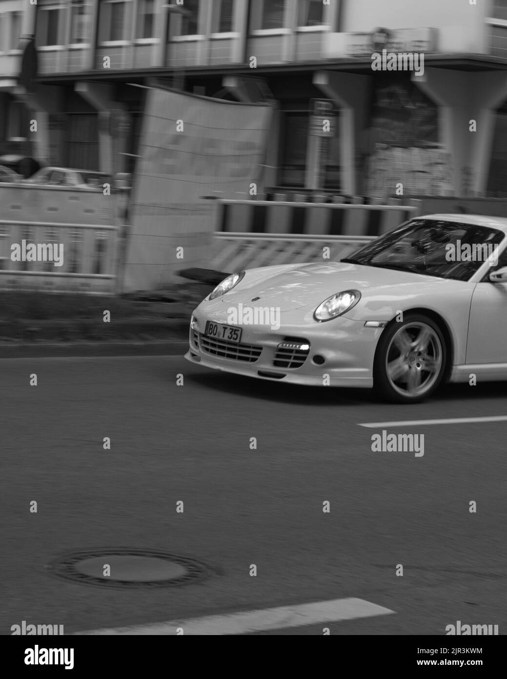 Une photo en niveaux de gris d'une Porsche 911 Turbo blanche de luxe en conduisant dans les rues de Bochum, en Allemagne Banque D'Images