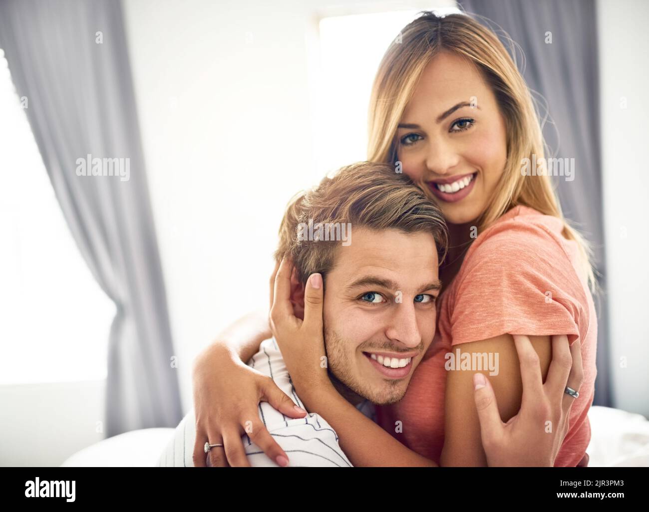 Son sourire inspire le mien. Un jeune couple heureux qui partage un moment affectueux au lit. Banque D'Images