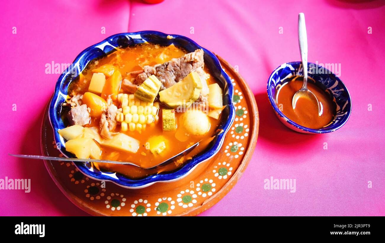 Assiette en argile avec pozole, cuisine mexicaine traditionnelle, nappe rose, cuillère en métal Banque D'Images