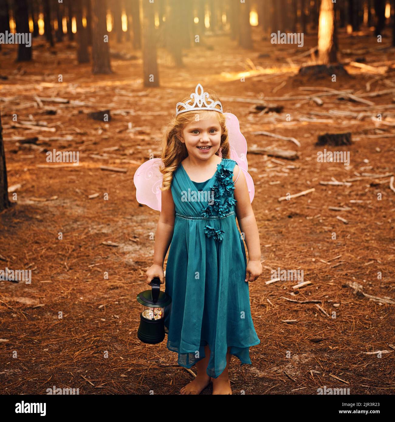 Je suis une véritable fée de la vie. Une petite fille heureuse regardant l'appareil photo et tenant une lampe tout en se tenant à l'extérieur dans les bois. Banque D'Images