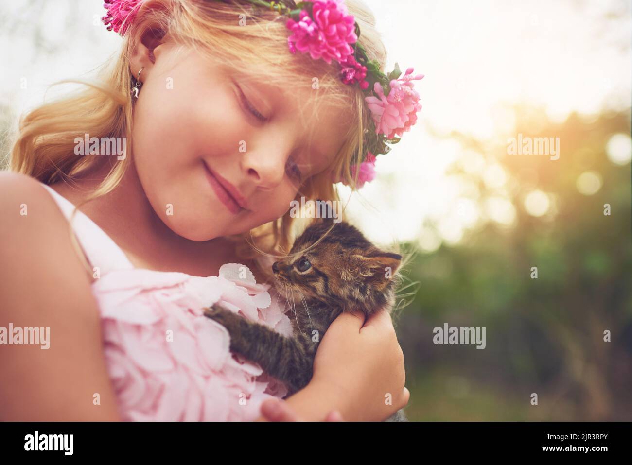 Mon ami furieux. Une petite fille heureuse tenant un chaton et souriant tout en étant assis dehors dans la nature. Banque D'Images