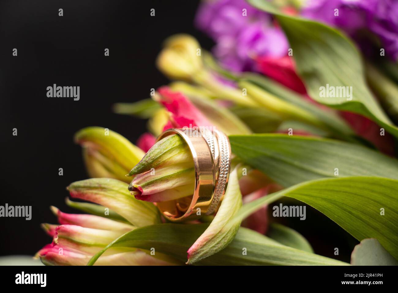 anneaux d'or de mariage de la mariée et du marié se trouvent sur le fond d'un bouquet de fleurs de la mariée, anneaux d'or au mariage Banque D'Images