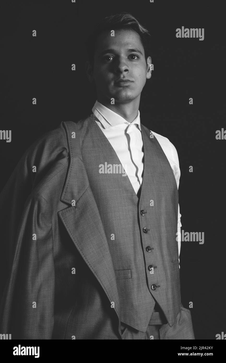 Homme élégant posant sur un fond noir. Photo en noir et blanc d'un homme en costume qui ressemble à un modèle. Photo de haute qualité Banque D'Images Homme élégant posant sur un fond noir. Photo en noir et blanc d'un homme en costume qui ressemble à un modèle. Photo de haute qualité Banque D'Images