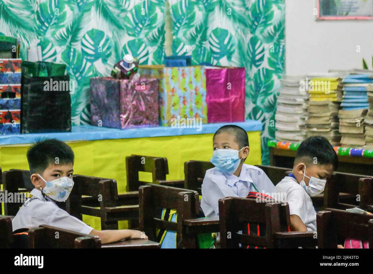Les élèves de l'école primaire s'assoient à l'intérieur de leur classe avant leur première classe. Les Philippines commencent des cours en personne après 2 ans de scolarité virtuelle en raison de la pandémie. Le ministère de l'éducation (DepEd) a déclaré qu'il y avait 27 691 191 apprenants inscrits pour l'année scolaire 2022-2023. Aux Philippines, 19 % des étudiants sont entièrement vaccinés et 20 % n'ont reçu que leur première dose du vaccin COVID-19, a déclaré DepEd. Le protocole du ministère est, s'il y a un cas de COVID-19 ou de certains étudiants qui éprouvent des symptômes grippaux, ils vont certainement passer des cours en personne à lear mélangé Banque D'Images