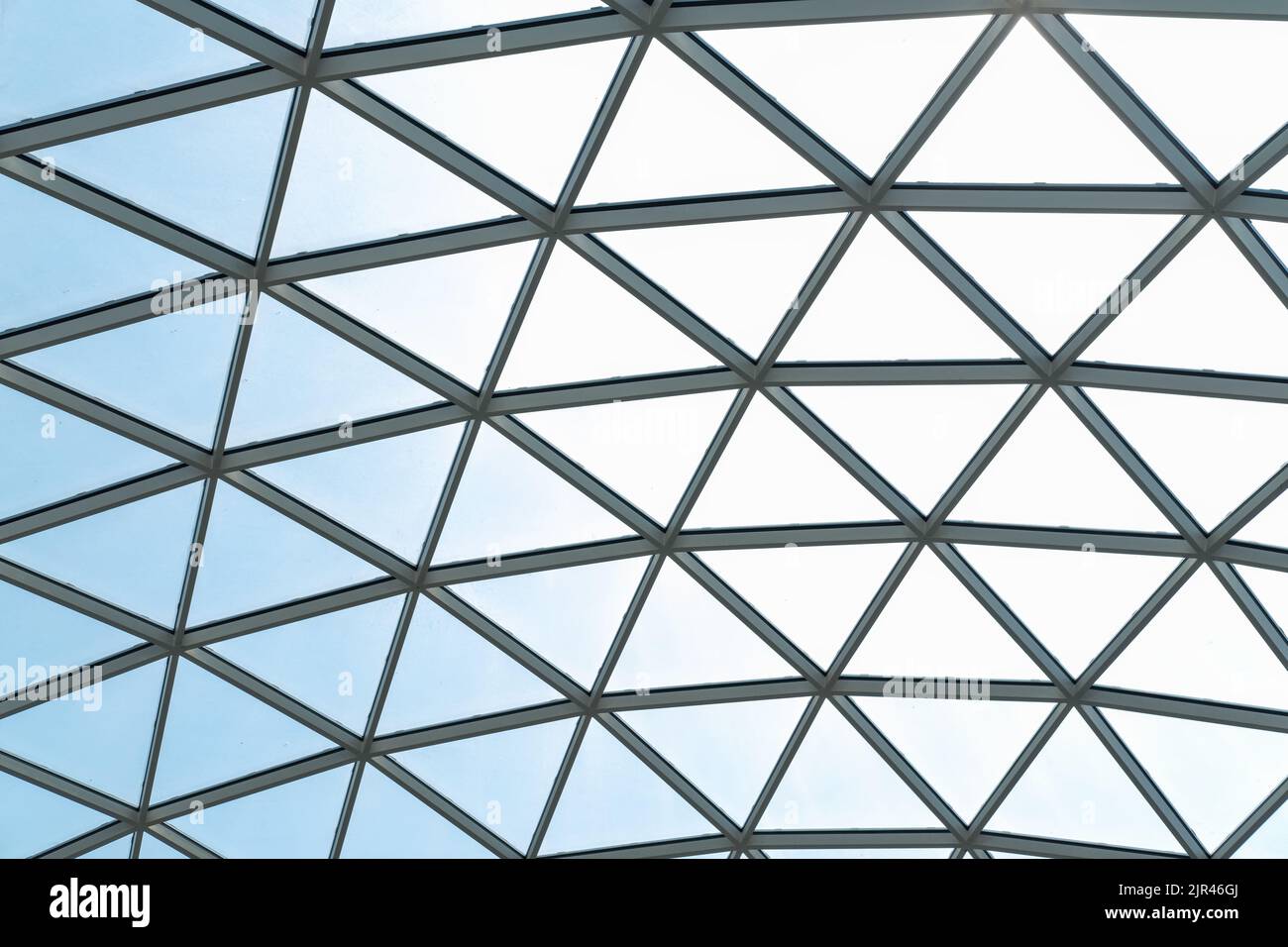 Structure en verre architecturale avec un motif géométrique triangulaire sur fond bleu ciel. Construction de mur de toit en verre d'acier fenêtre transparente avec Banque D'Images