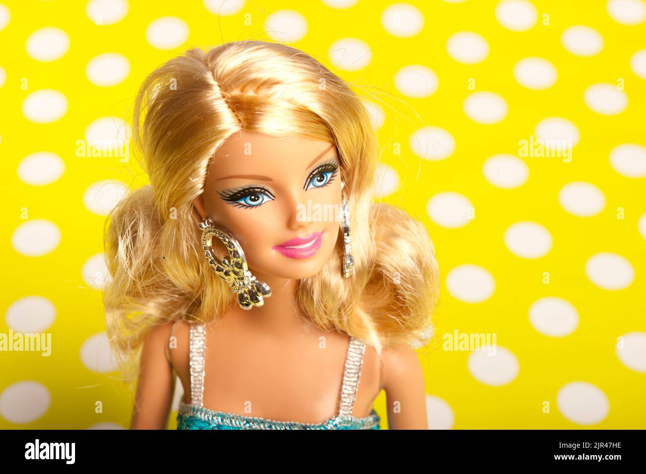 Barbie blonde avec robe bleue sur fond de pois jaunes Banque D'Images