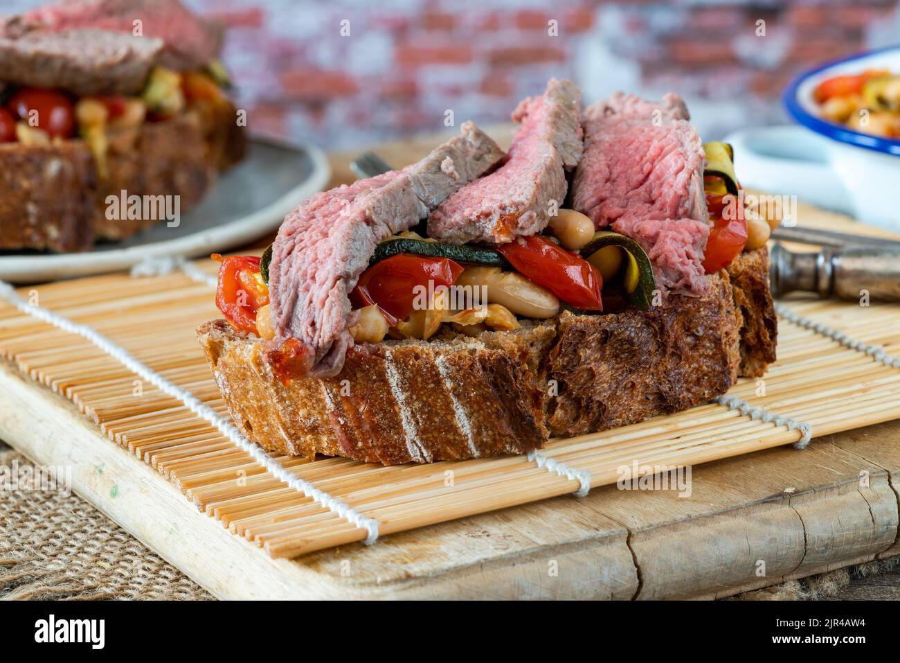 Steak de bœuf sur levain avec tomates garlicky, courgettes et haricots cannellini Banque D'Images