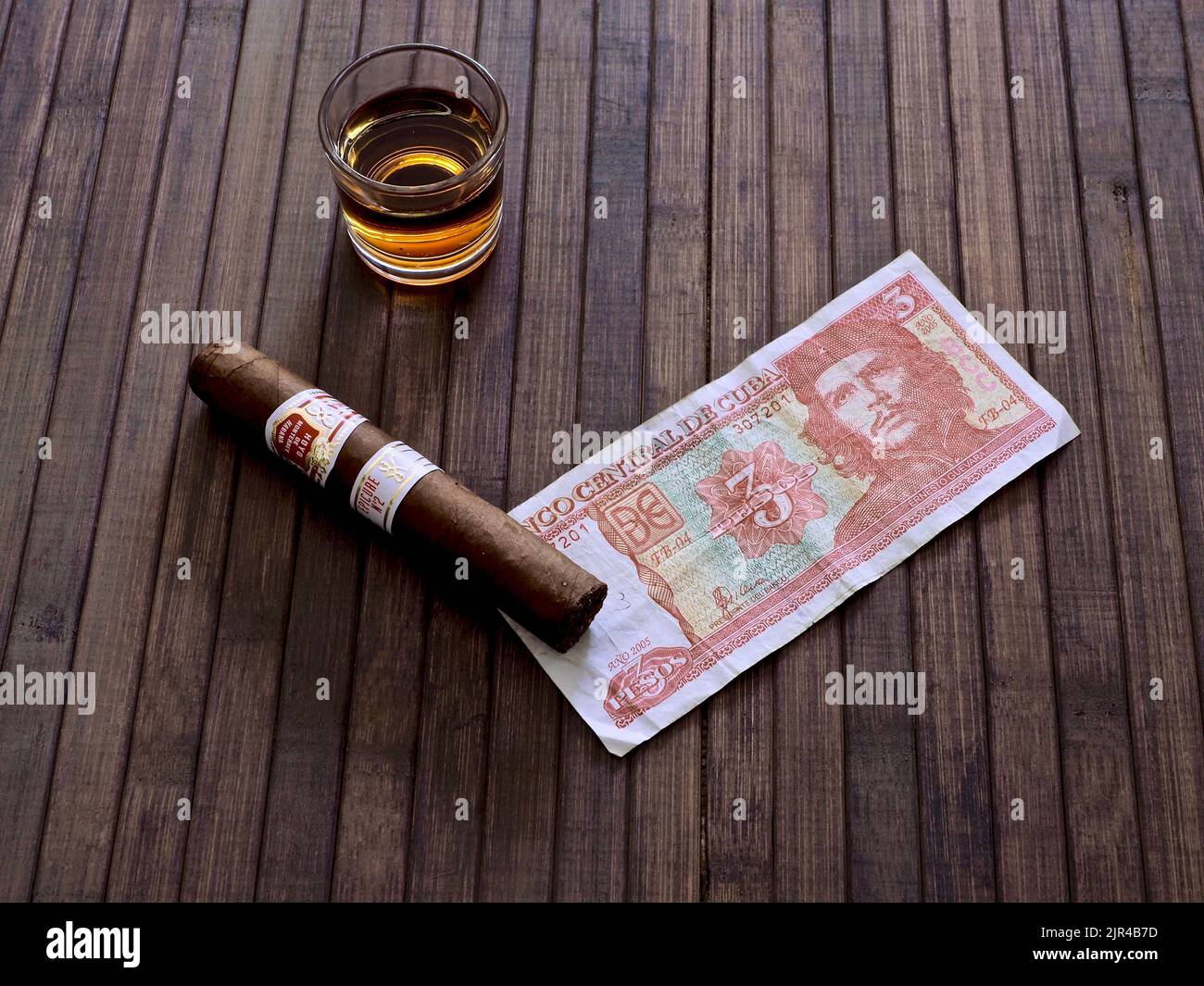 Un cigare, un dollar cubain et un verre de rhum sur une table en bois Banque D'Images