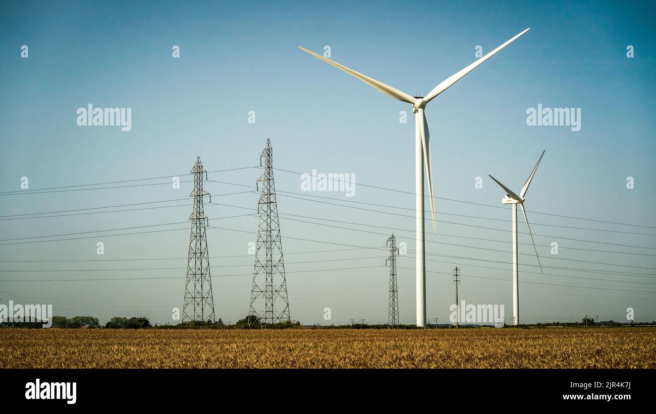 Éolienne et pylônes sur un ciel bleu Banque D'Images