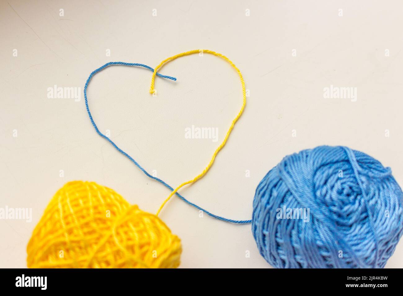 Forme en forme de coeur avec des fils colorés. Fils bleus et jaunes en forme de coeur. Couleurs nationales ukrainiennes. Le patriotisme. Passe-temps en tricot. Banque D'Images