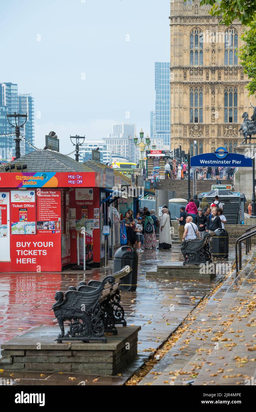 Touristes et touristes aux stands de vente de billets d'excursion lors d'une journée de pluie à Westminster Pier. Londres, Angleterre, Royaume-Uni. Banque D'Images