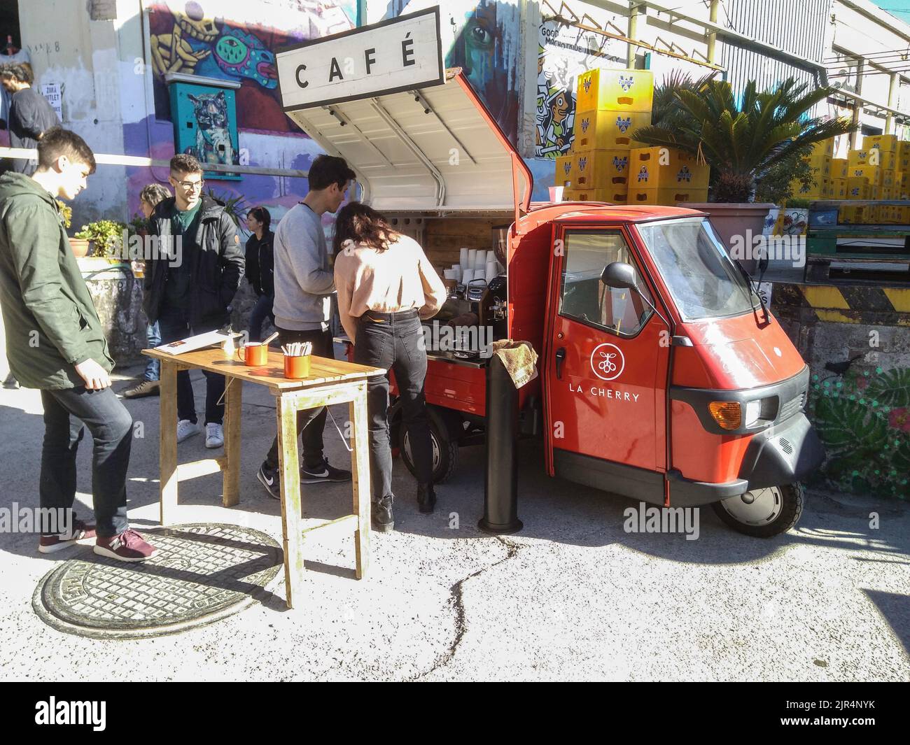 Les gens près d'un rouge classique Piaggio APE trois roues garées dans la rue Banque D'Images