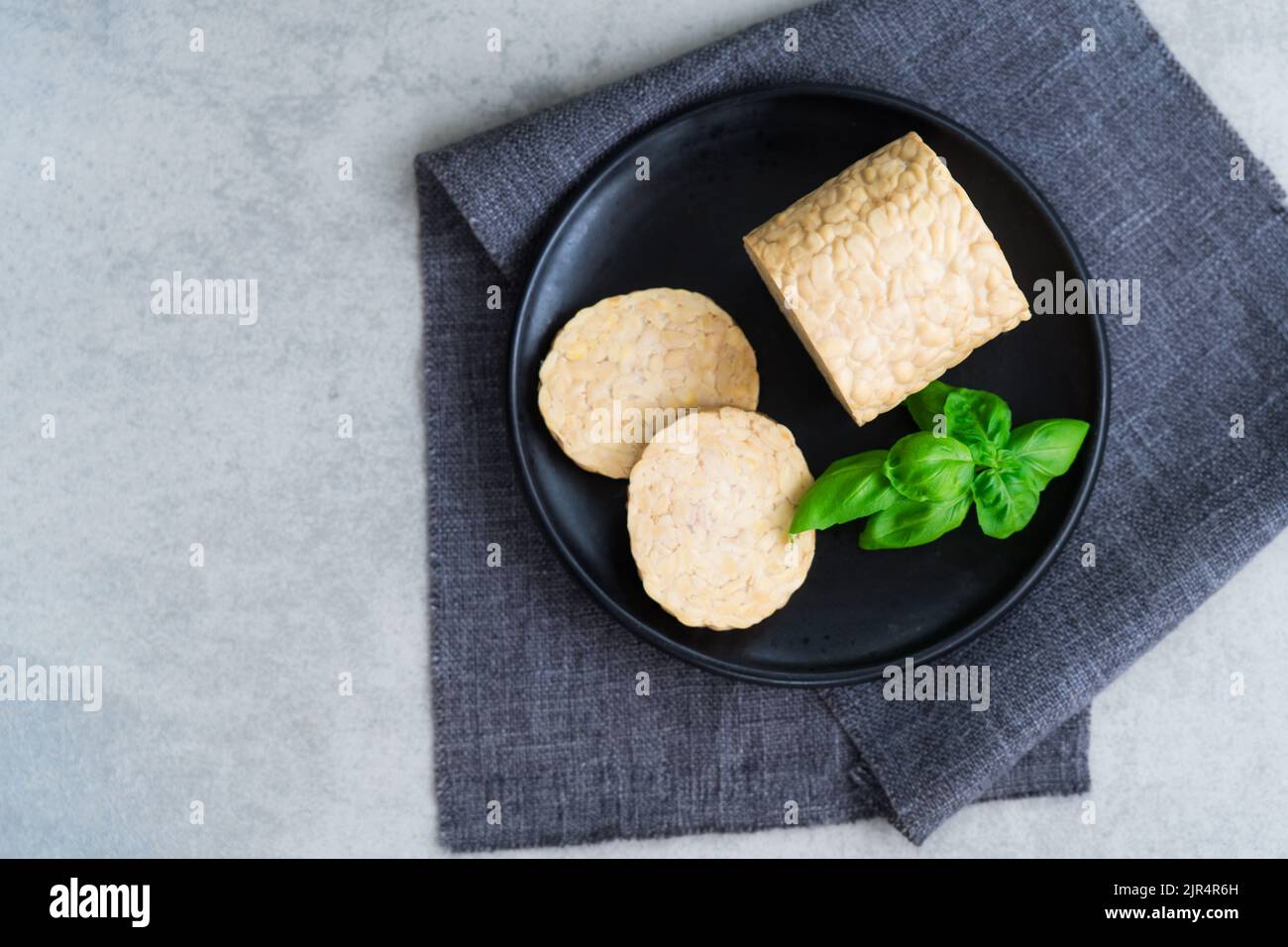 Vue de dessus tempeh ou tempeh cru, fait de graines de soja fermentées. Tranches de tempeh sur l'assiette avec des herbes. Protéines de soja. Concept de viande à base de plantes. Coo sain Banque D'Images Vue de dessus tempeh ou tempeh cru, fait de graines de soja fermentées. Tranches de tempeh sur l'assiette avec des herbes. Protéines de soja. Concept de viande à base de plantes. Coo sain Banque D'Images