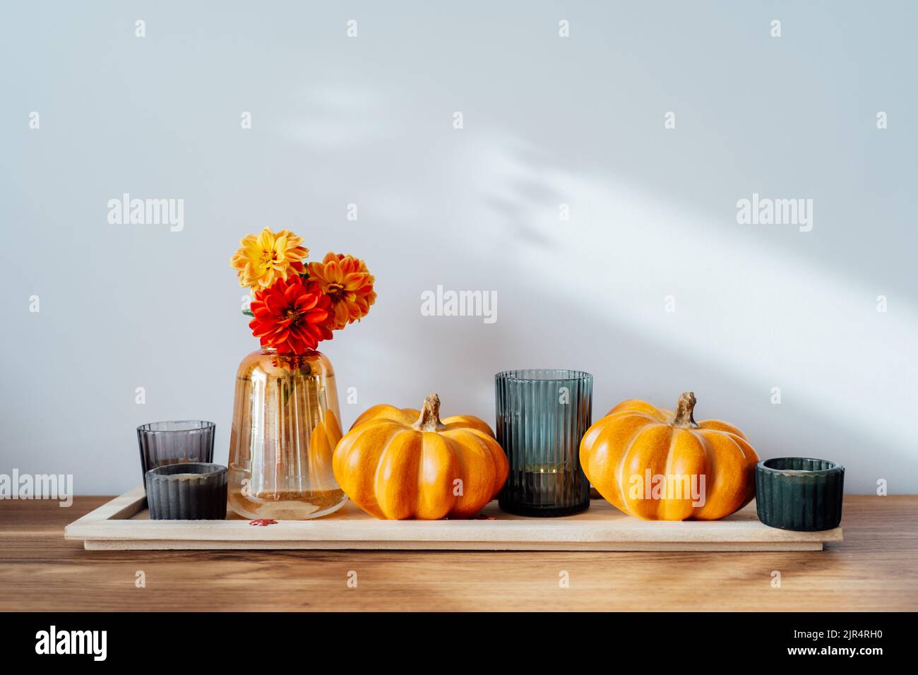 Automne, automne composition confortable. Citrouilles d'orange, bougies, fleurs de dahlia dans un vase sur le plateau en bois de la table avec fond de mur blanc. Scandinave Banque D'Images Automne, automne composition confortable. Citrouilles d'orange, bougies, fleurs de dahlia dans un vase sur le plateau en bois de la table avec fond de mur blanc. Scandinave Banque D'Images