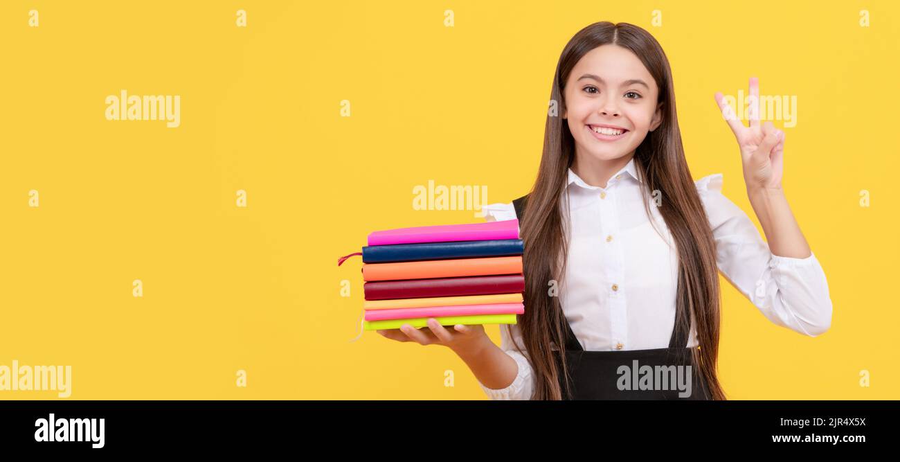 bonne adolescente fille dans l'uniforme d'école tenir pile de livre montrer la paix geste, éducation. Portrait de l'élève d'une écolière, en-tête de bannière de studio. Enfant de l'école Banque D'Images