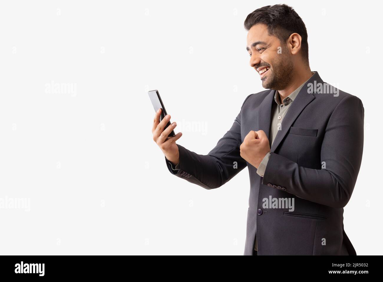 Un jeune homme d'affaires enthousiaste qui regarde le téléphone portable Banque D'Images