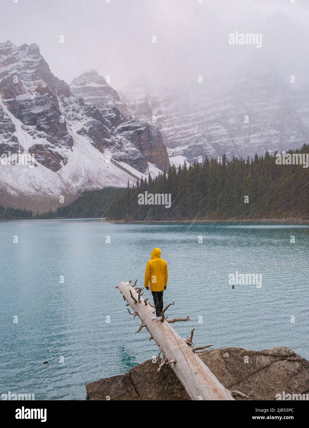 Lac Moraine pendant une journée de neige froide en automne au Canada, de belles eaux turquoise du lac Moraine avec de la neige. Couple d'hommes et de femmes en manteau de pluie jaune pendant la neige Banque D'Images