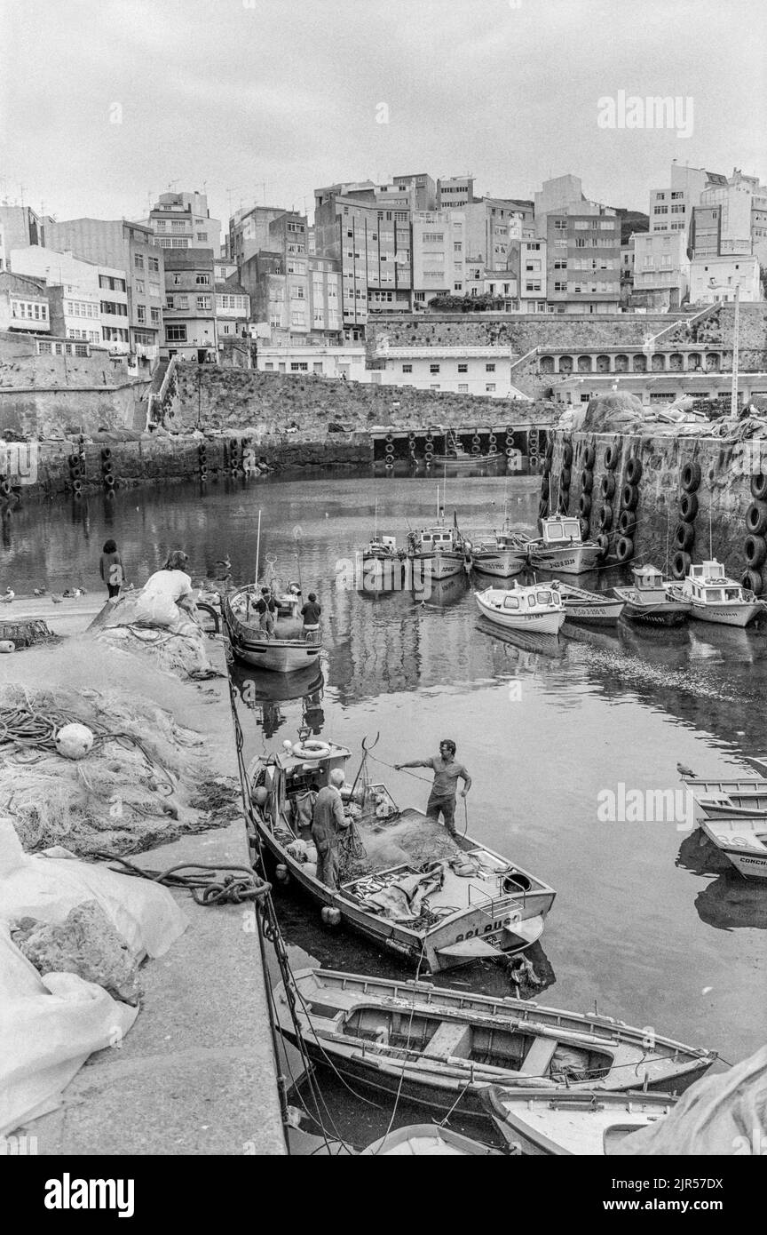 ESPAGNE - Galice - 1970s. Pêcheurs préparant leurs bateaux dans le port de Malpica avec la ville en arrière-plan., Galice, Nord-Ouest de l'Espagne. Copyright Pho Banque D'Images