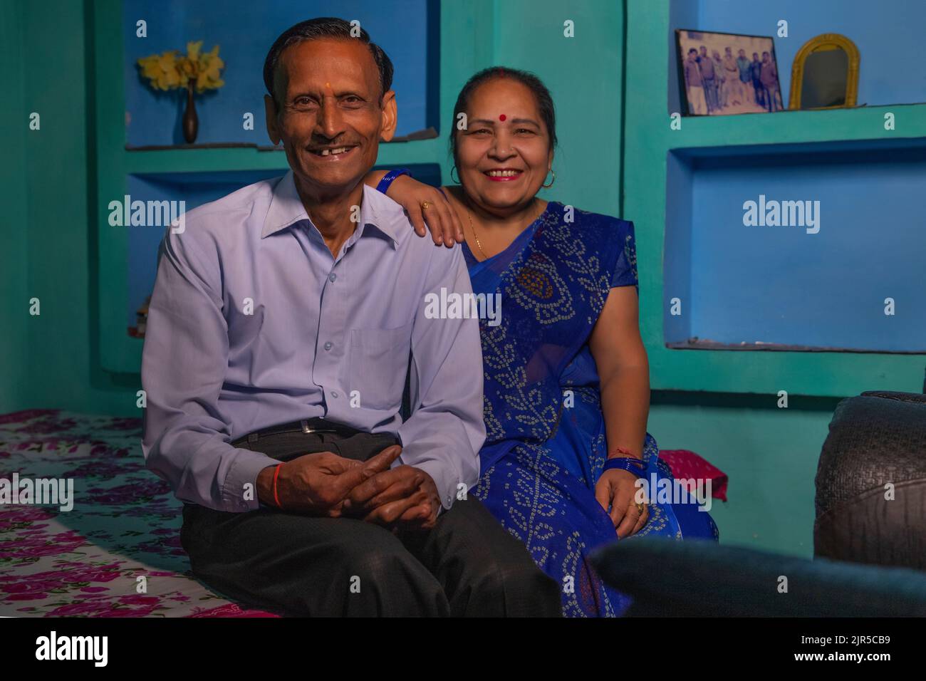 Portrait d'un couple senior regardant l'appareil photo tout en étant assis sur le lit Banque D'Images