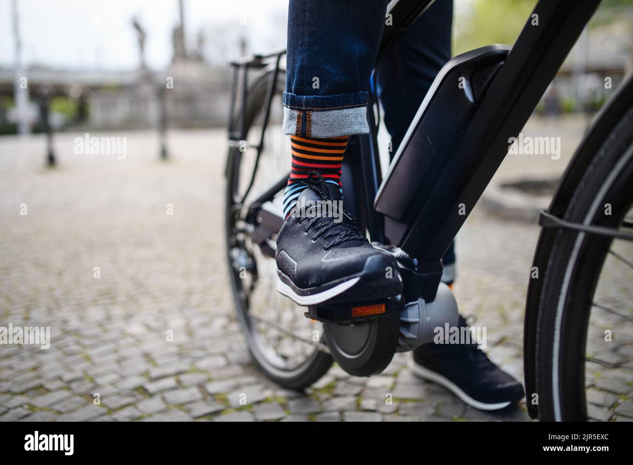 Homme d'affaires se rendant au travail, gros plan sur ses jambes à vélo. Banque D'Images