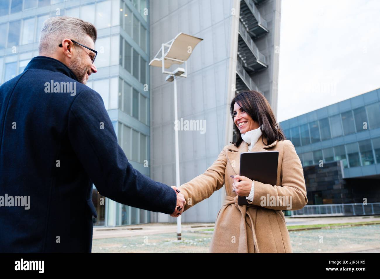 Homme d'affaires entre la main avec un partenaire devant les immeubles de bureaux de la ville - accueil, négociation, fusion et acquisition de concepts Banque D'Images