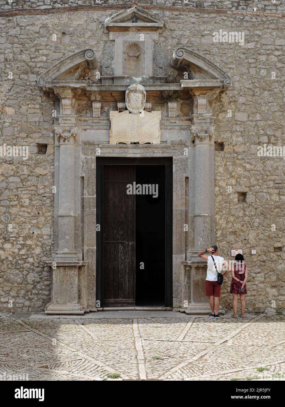 Couple de touristes lisant un panneau touristique à côté du portail d'entrée baroque de la salle de conjeuring dans le château de Caccamo dans l'ouest de la Sicile, Italie Banque D'Images