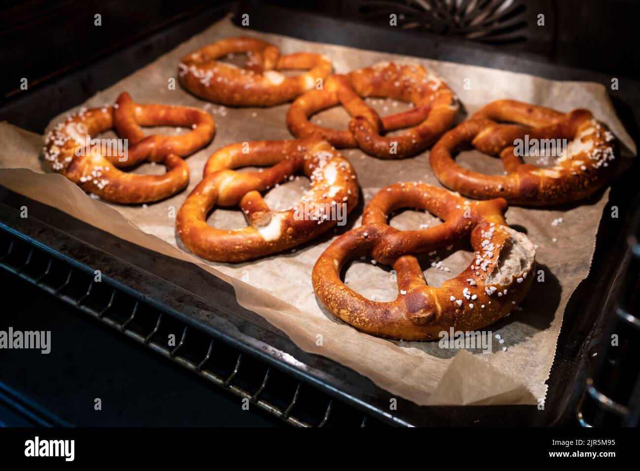 Les bretzels cuits avec ajout de gros sel reposent sur une plaque de cuisson dans le four. Cuisine allemande traditionnelle. Oktoberfest. Banque D'Images