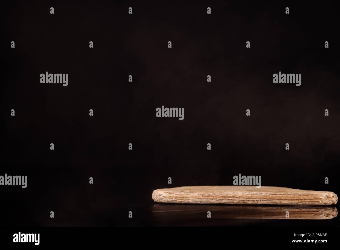 Plate-forme minimaliste en bois pour la présentation des produits. Arrière-plan noir. Banque D'Images