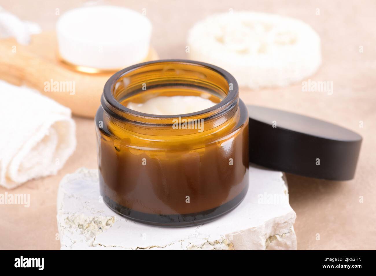 Ouvert pot crème hydratante dans un flacon en verre ambré sur podium en pierre et set pour les produits de soins de la peau et du corps sur fond beige. moc d'emballage cosmétique Banque D'Images