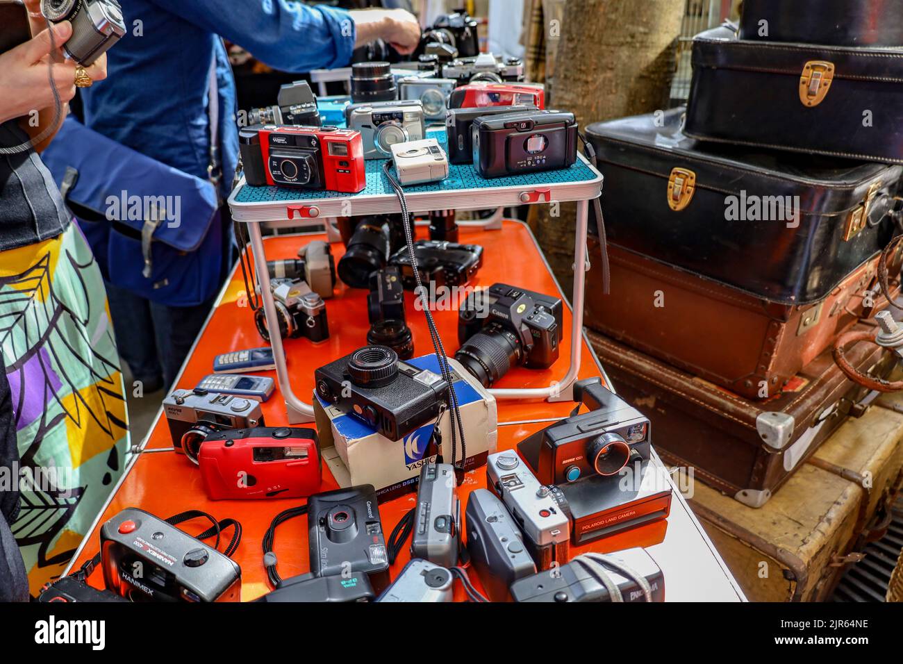Un tas d'anciens appareils photo d'époque exposés sur une table rouge à un marché aux puces de Paris, en France Banque D'Images