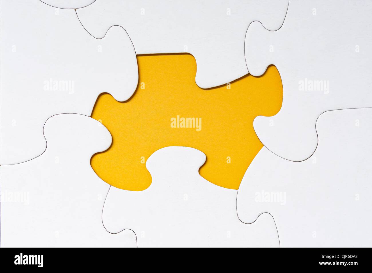 Puzzle blanc avec quelques pièces manquantes sur fond jaune. Copier l'espace. Banque D'Images