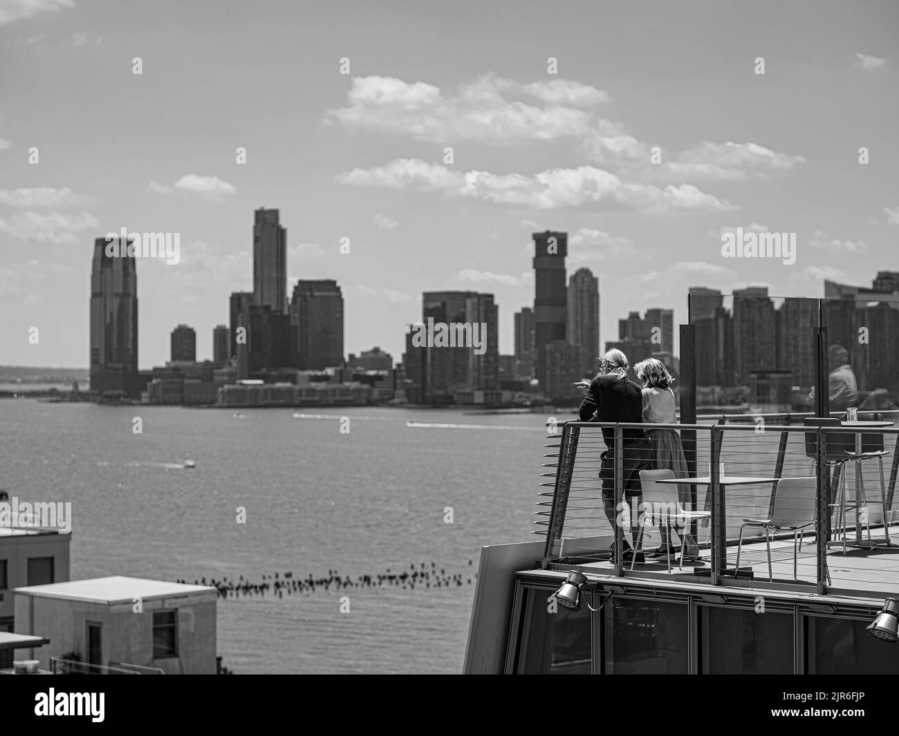 Photo en niveaux de gris d'un couple qui se penche sur une rampe et qui admirent la vue sur la mer Banque D'Images