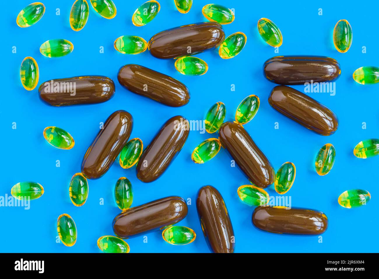 Pilules de différentes couleurs et tailles sur fond bleu. Vue de dessus, plan d'appartement Banque D'Images