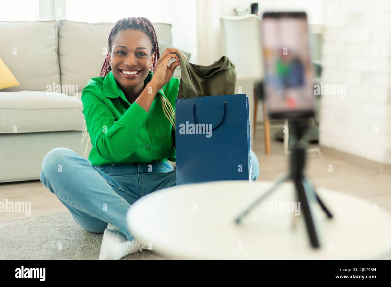 Vidéo de déballage. Happy female mode blogger enregistrement de contenu pour son style blog, en utilisant smartphone sur trépied Banque D'Images