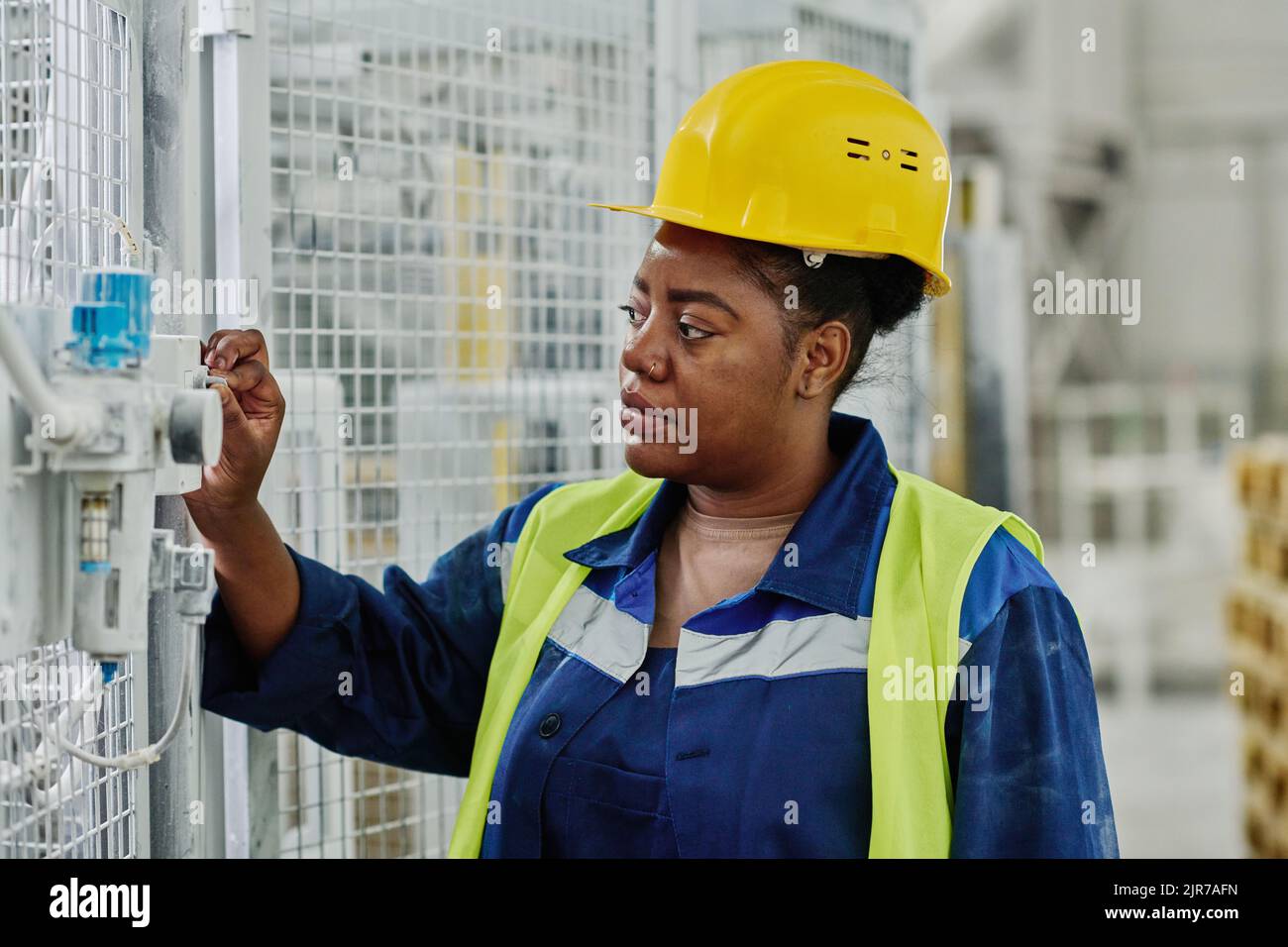 Jeune femme ingénieure qui se charge de l'équipement industriel avant de travailler sur la production de machines dans une usine moderne Banque D'Images