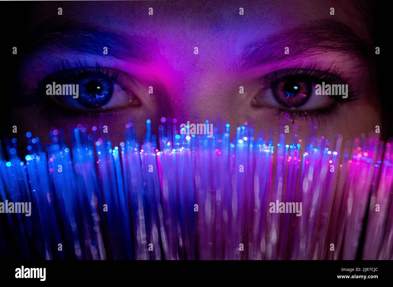 Femme regarde à travers le millénaires de bokeh de couleur sarcelle futuriste, femme fille regardant la caméra avec la technologie avancée de fibre optique, Noël Banque D'Images