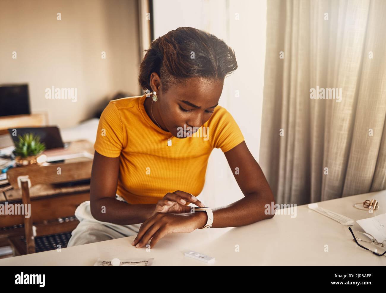 Jeune femme noire inquiète et stressée en attente des résultats du test Covid. Femme afro-américaine regardant l'époque sur une montre intelligente et inquiète Banque D'Images