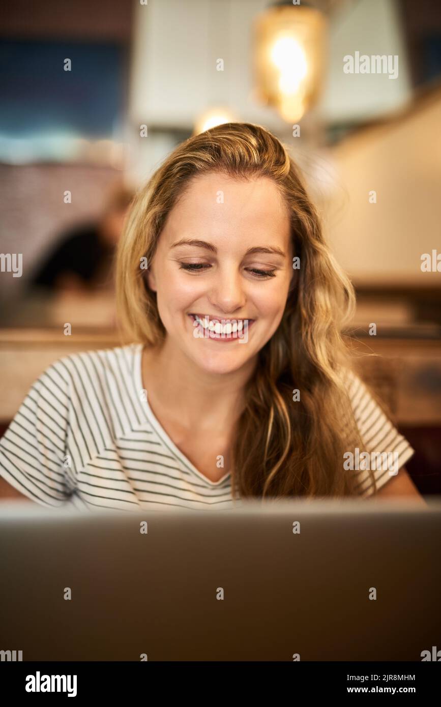 Allons commencer cet essai. Un jeune étudiant heureux utilisant son ordinateur portable pour étudier à une table de café. Banque D'Images