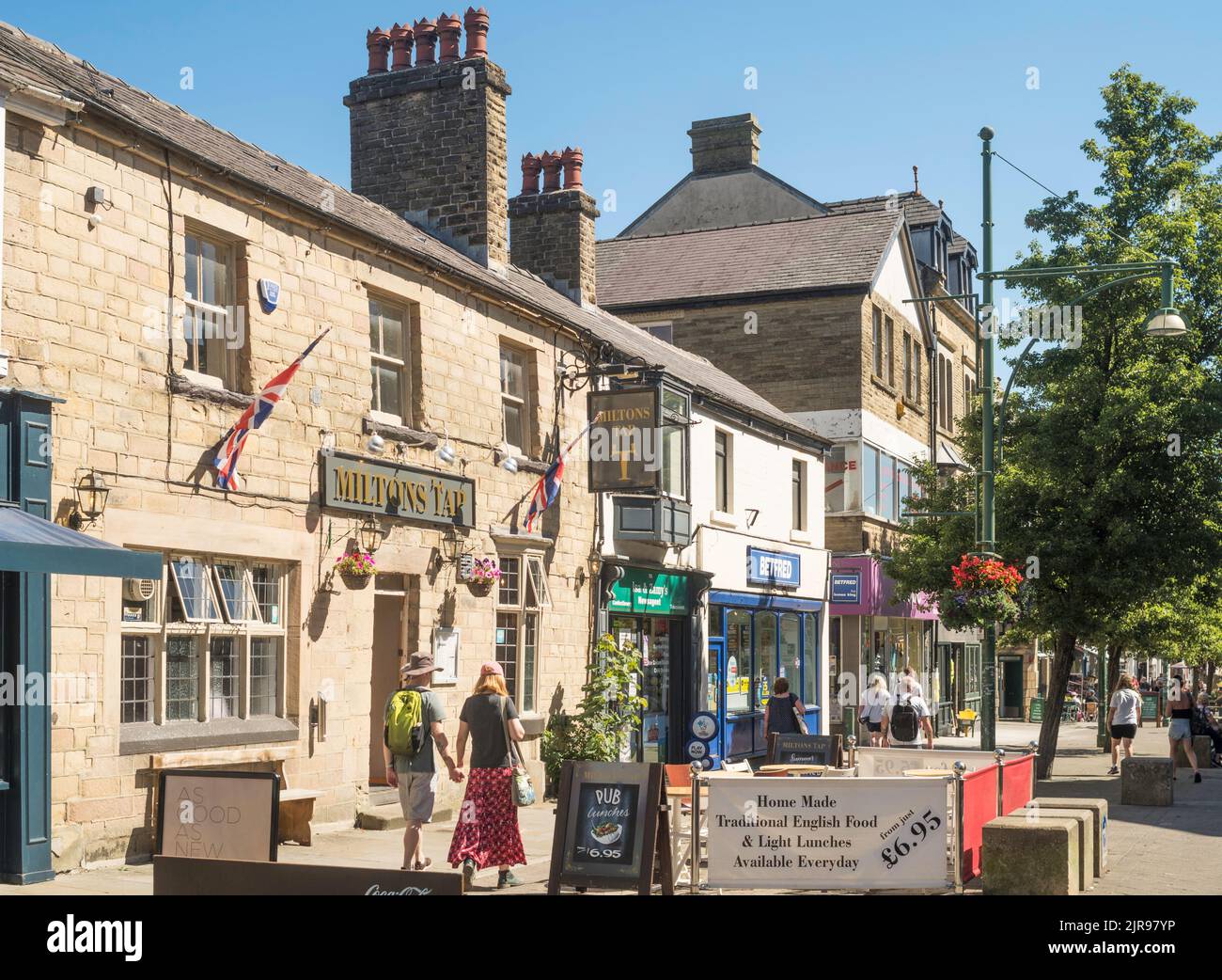 Un couple qui passe devant le pub Miltons Tap dans le centre-ville de Buxton, Derbyshire, Angleterre, Royaume-Uni Banque D'Images