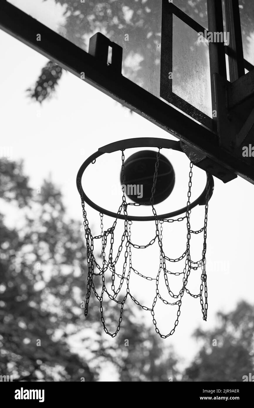 Ballon de basket-ball de rue tombant dans le panier. Photo en noir et blanc. Concept de réussite, points de pointage et de victoire Banque D'Images