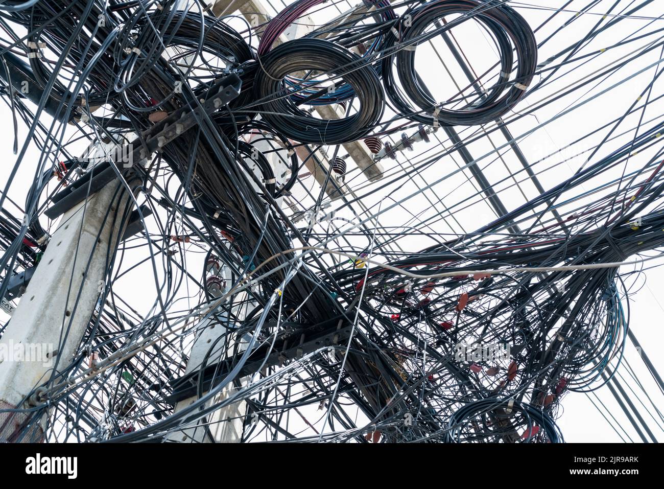 Fils électriques emmêlés sur le pôle électrique urbain. Désorganisé et ...