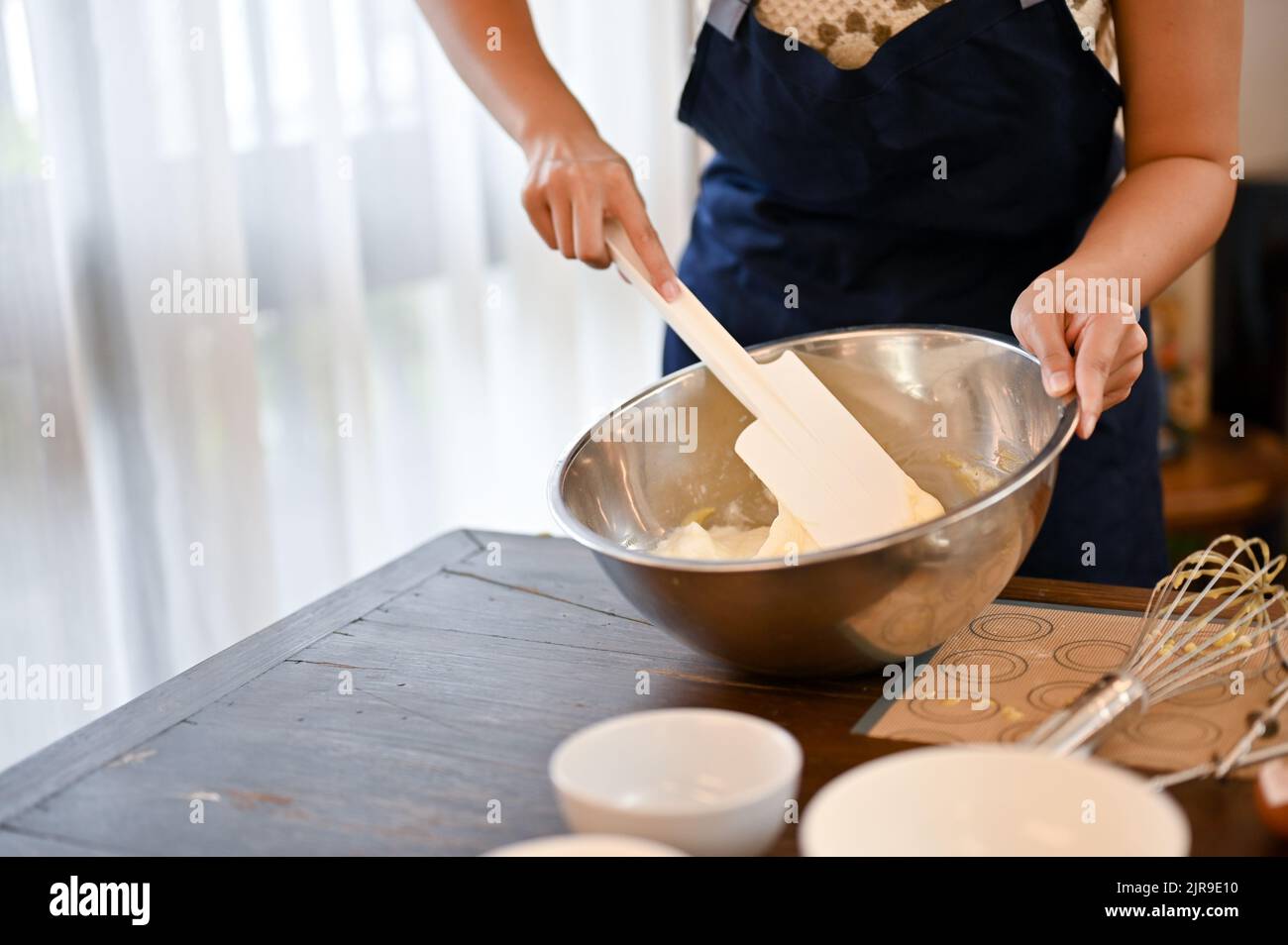 Une boulangère qui cuit un savoureux cupcake dans la cuisine, fouetter le mélange de farine dans le bol avec une spatule en plastique jusqu'à ce que le mélange soit combiné. Cupcak Banque D'Images