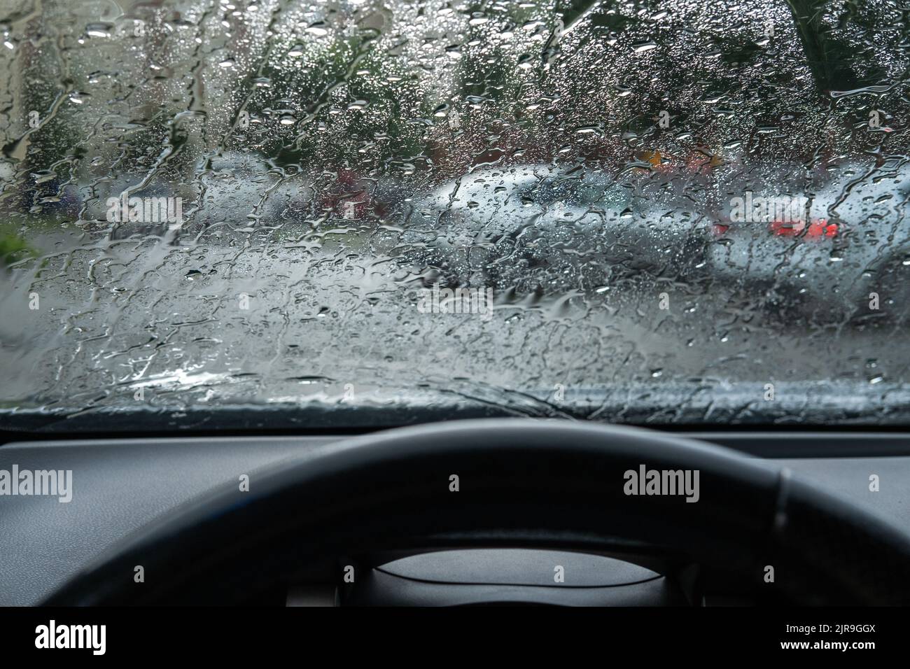 Gouttes de pluie floues sur le parebrise de la voiture. Le conducteur est dans la circulation