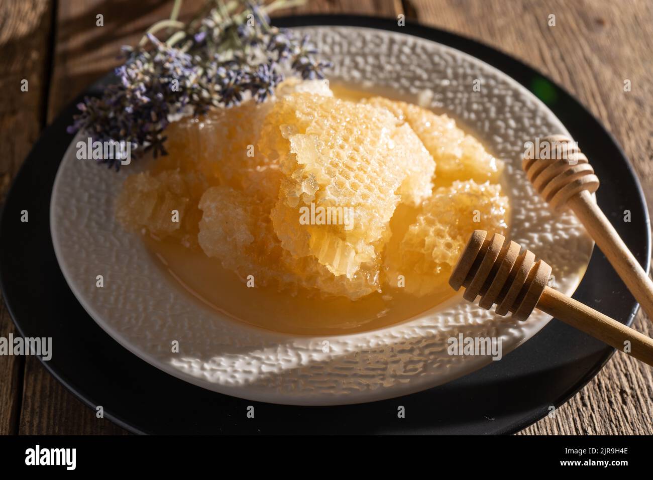 Miel et nid d'abeilles sur une assiette blanche. Des aliments sucrés dans un bol sur la table. Un produit d'apiculture. Fleur de lavande. Banque D'Images