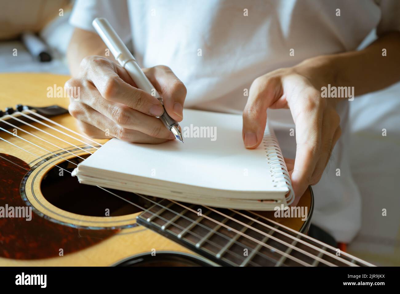 Musicien utilisant un stylo et un bloc-notes pour écrire une chanson Banque D'Images