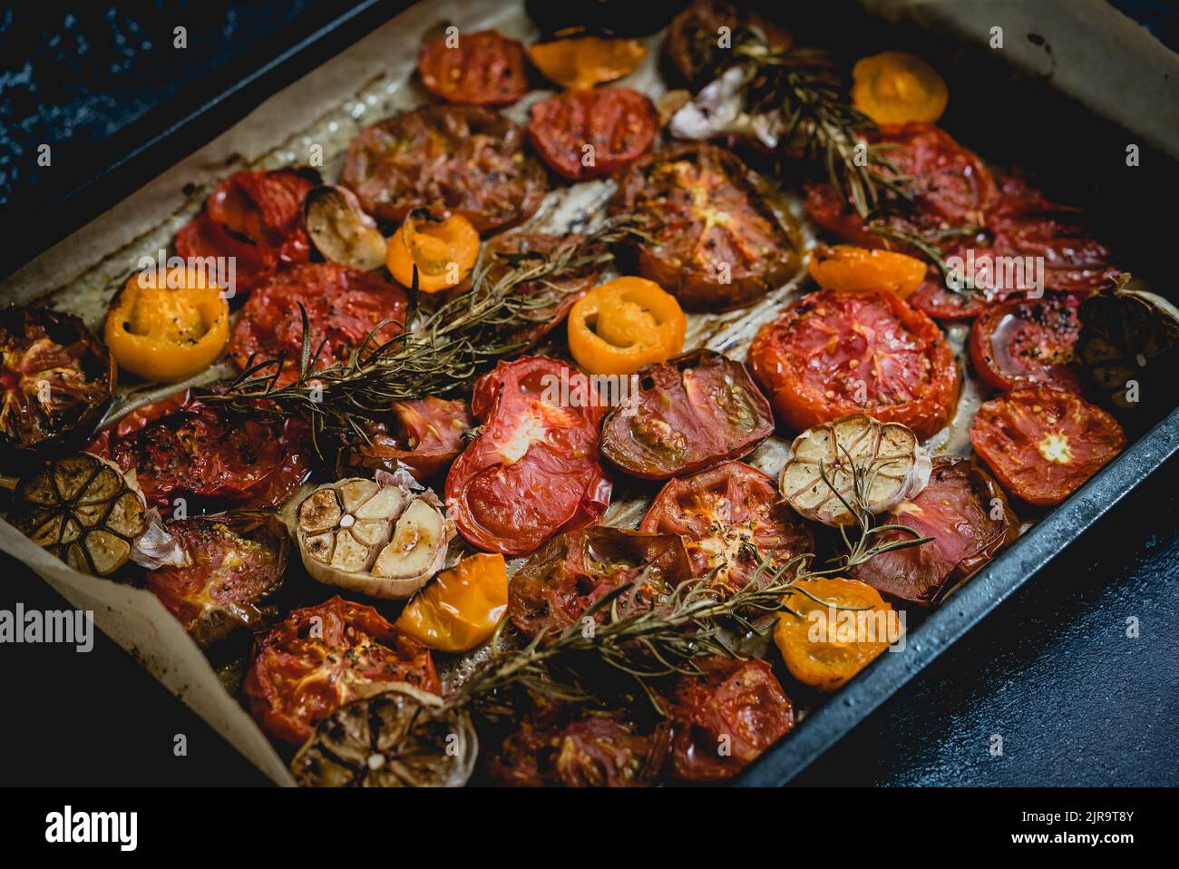 Plateau en métal avec rôti à l'ail et aux herbes différentes couleurs et de différentes sortes de tomates Banque D'Images