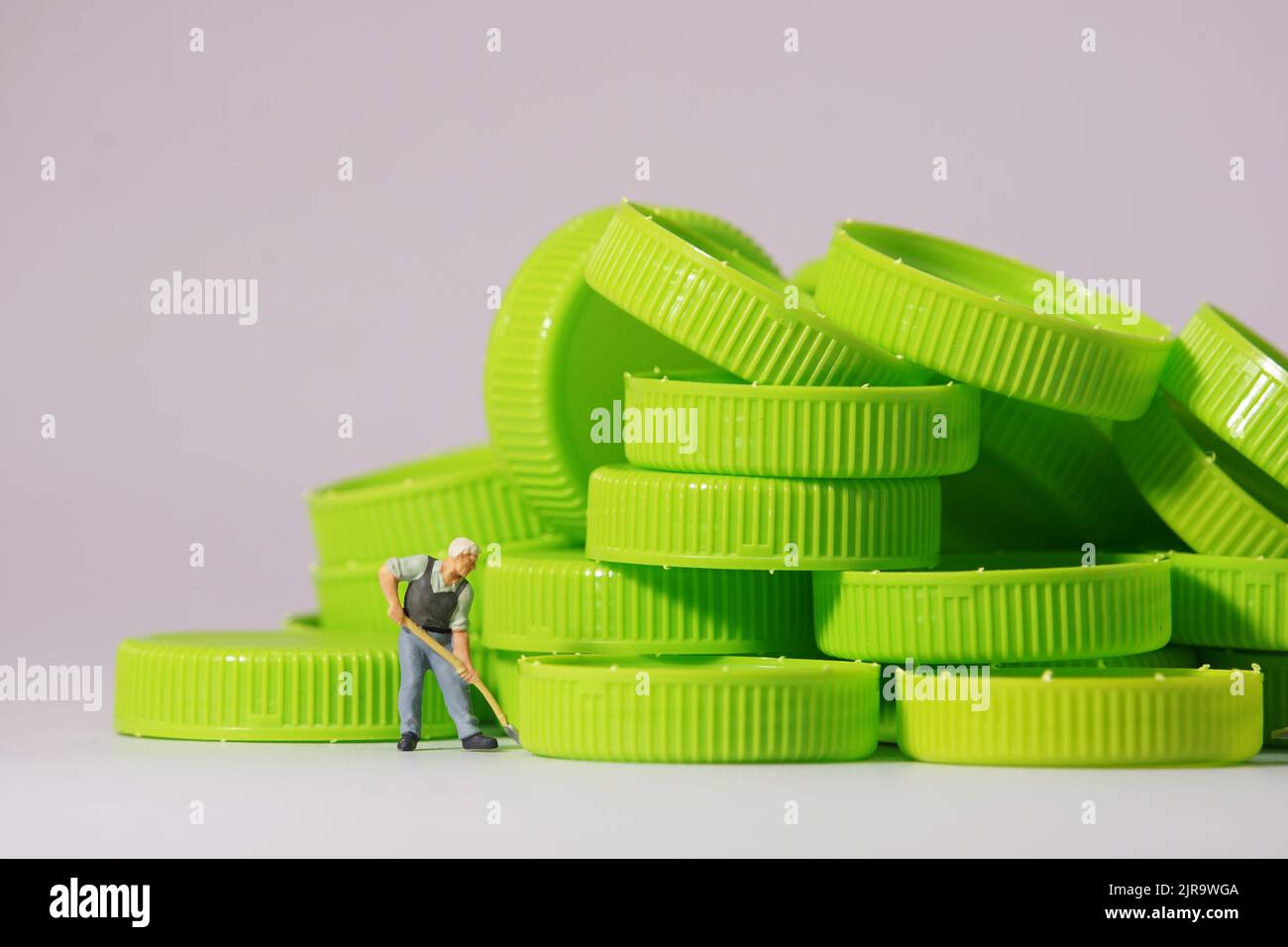 Figure de travailleur debout sur un capuchon en plastique. Concept de recyclage des matériaux. Banque D'Images